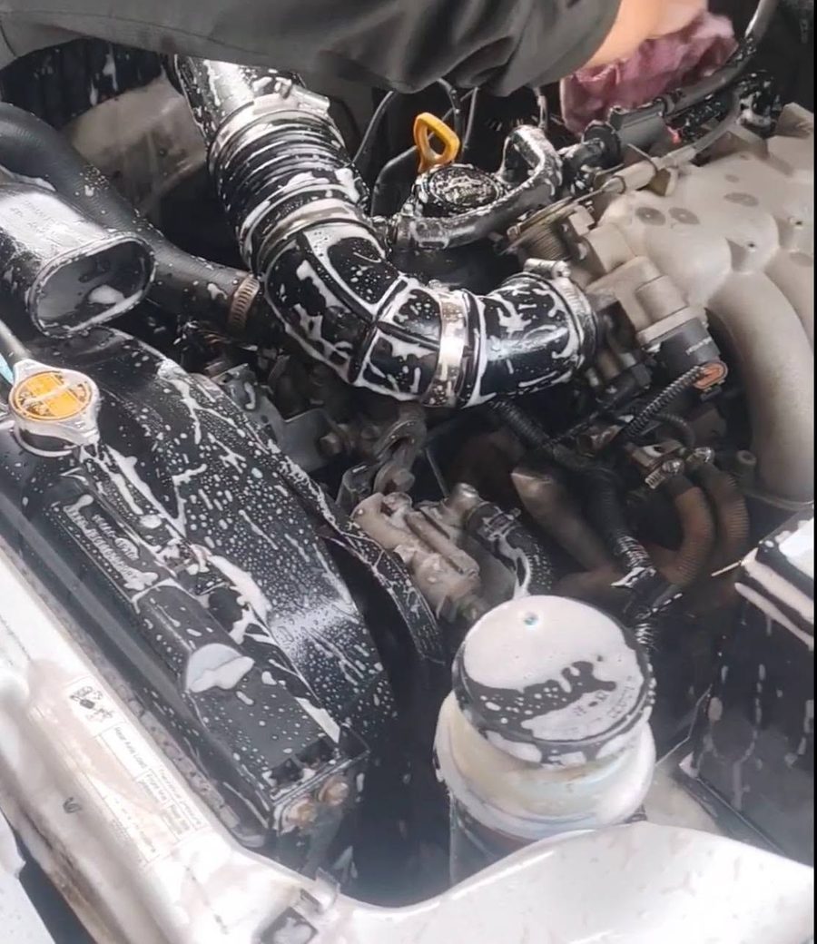 Close-up of an engine bay being cleaned during a service.